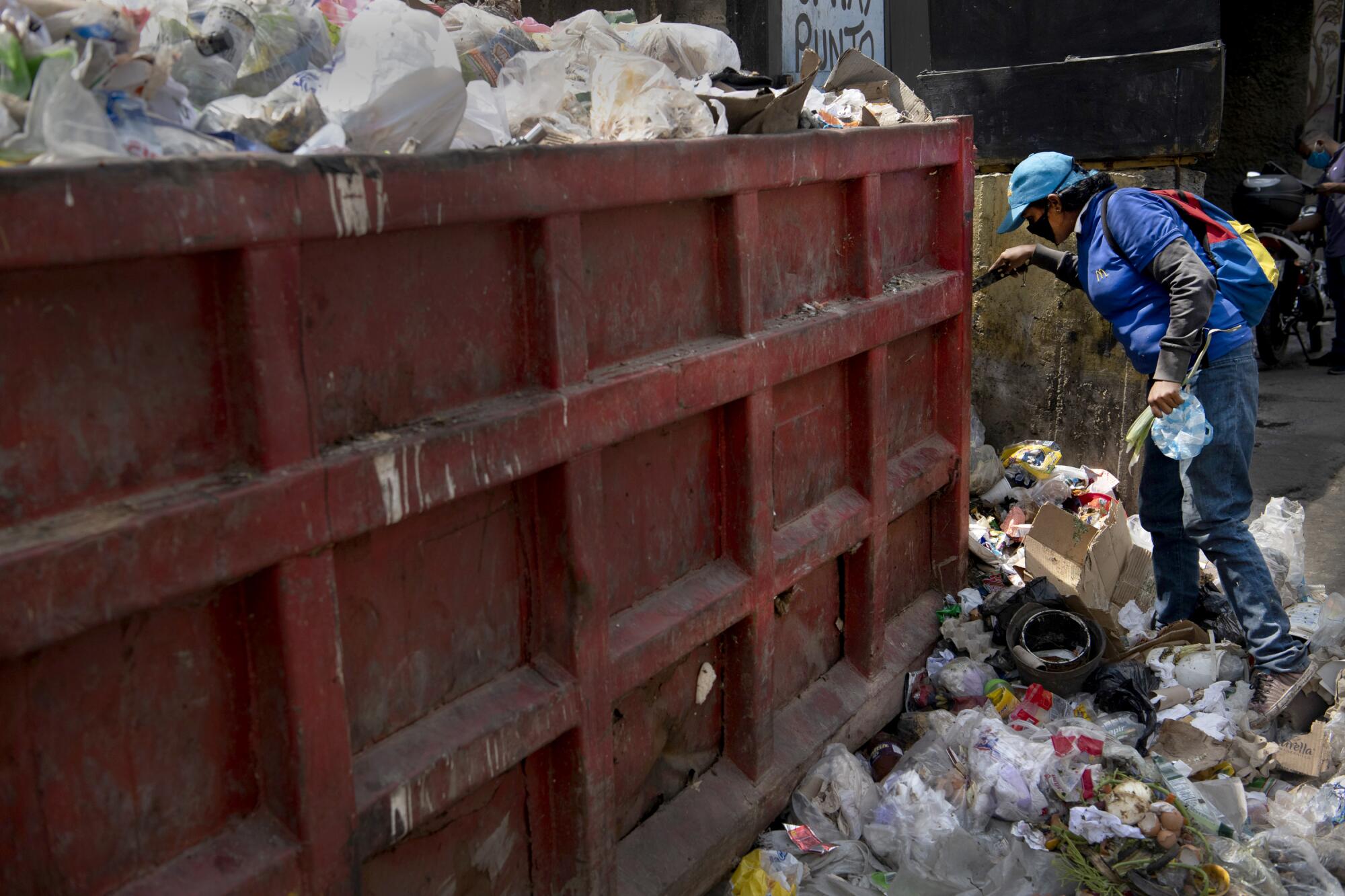 A person digs into the garbage for food in Caracas, Venezuela. 