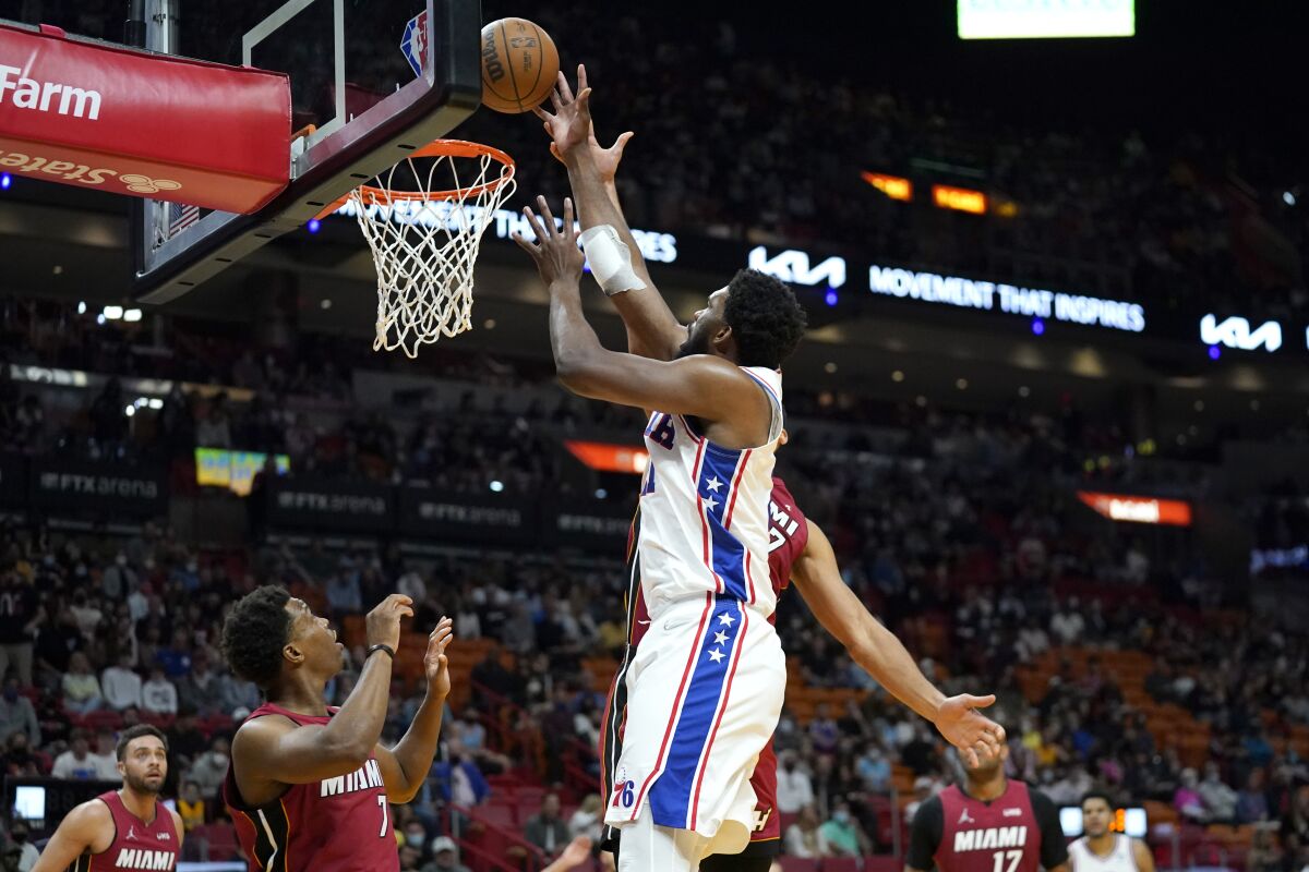 Philadelphia 76ers center Joel Embiid,, right, shoots over Miami Heat guard Kyle Lowry (7) during the first half of an NBA basketball game, Saturday, Jan. 15, 2022, in Miami. (AP Photo/Lynne Sladky)