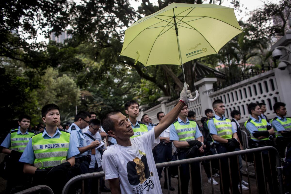 A Hong Kong pro-democracy protester holds an umbrella in front of police guarding Government House after a march from the Admiralty protest site on Oct. 22.