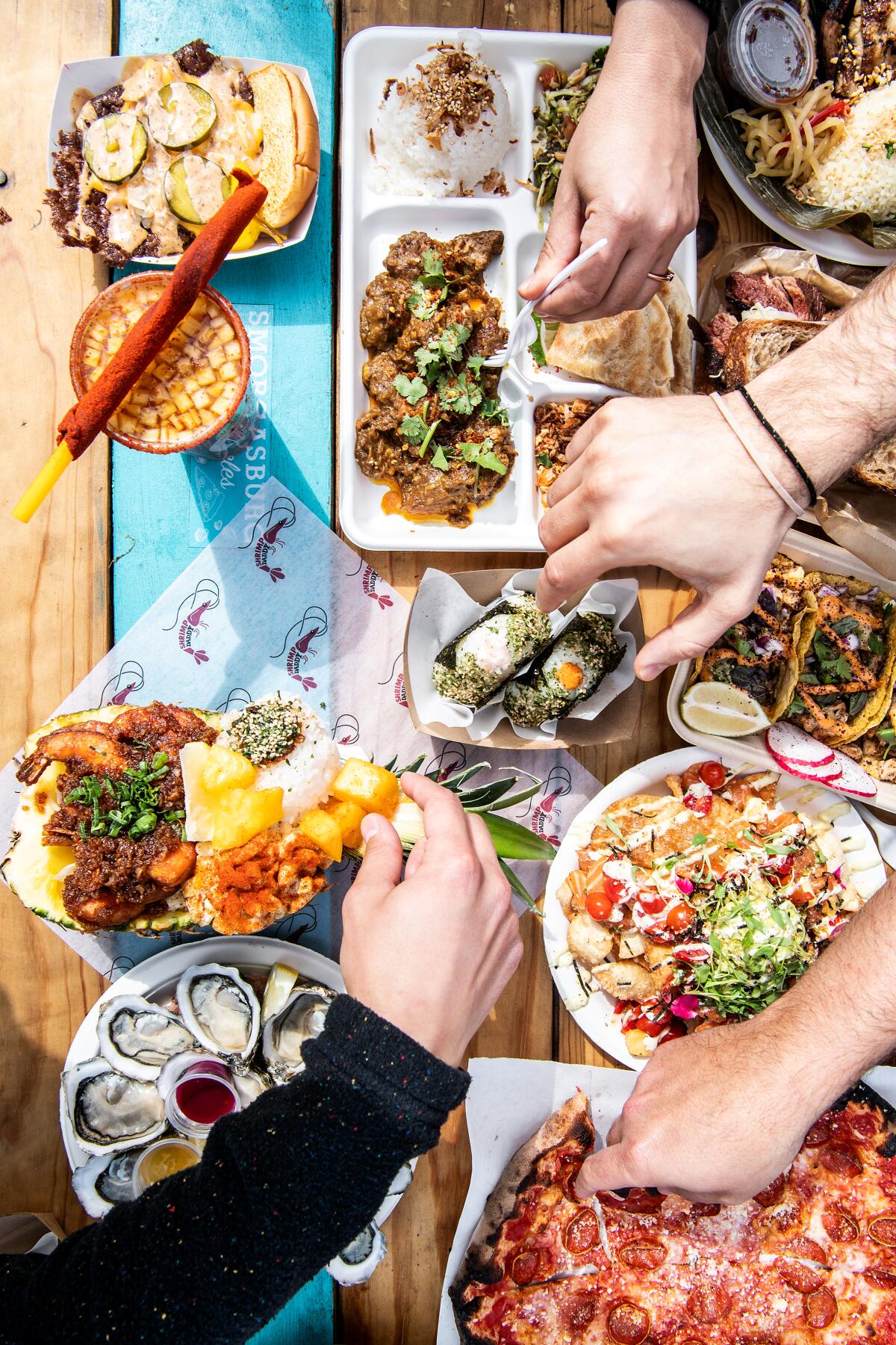 Hands reaching in to share a variety of dishes on a table.