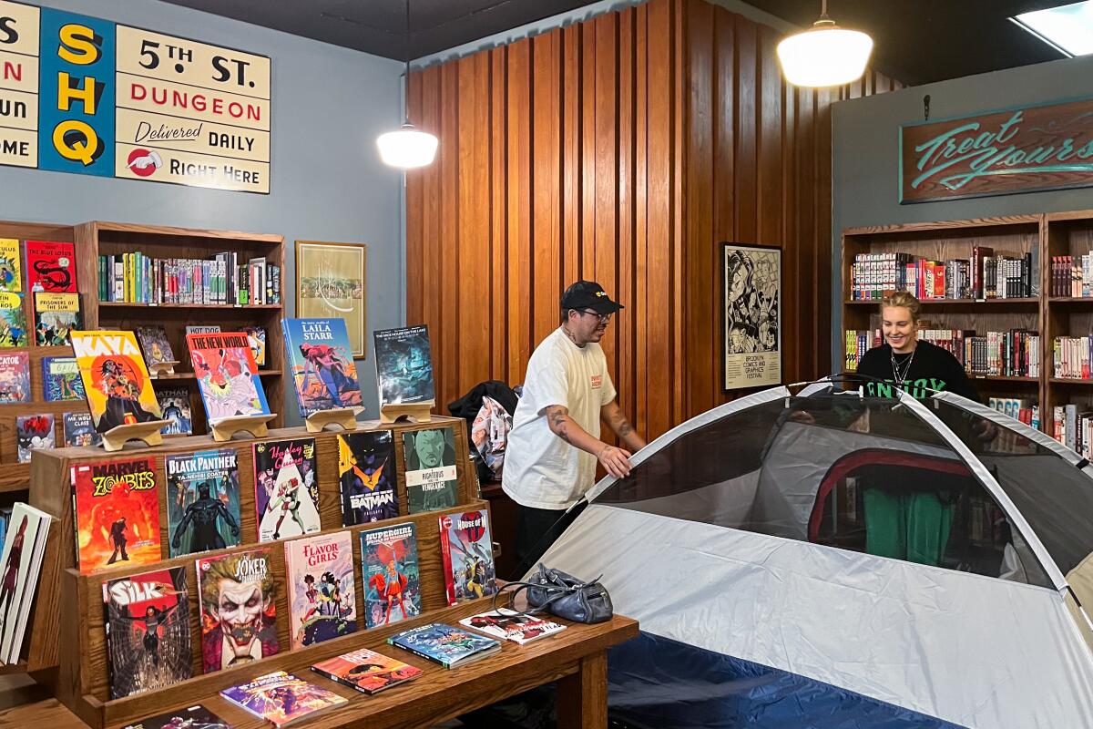 Two people set up a tent inside a bookstore.