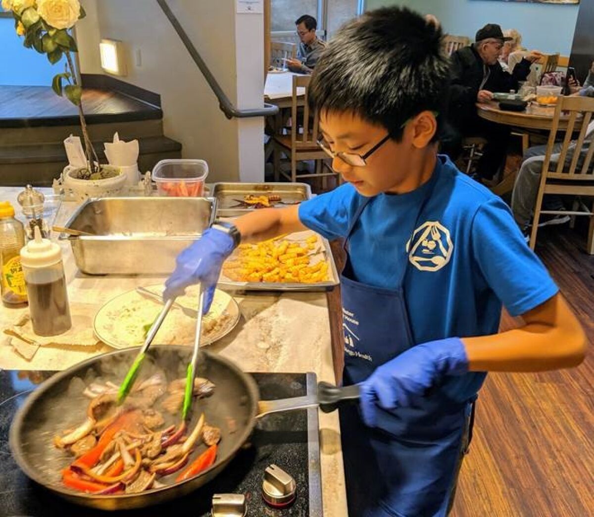 Aiden Lo cooking dinner for a hospital guest at UC San Diego Bannister House.