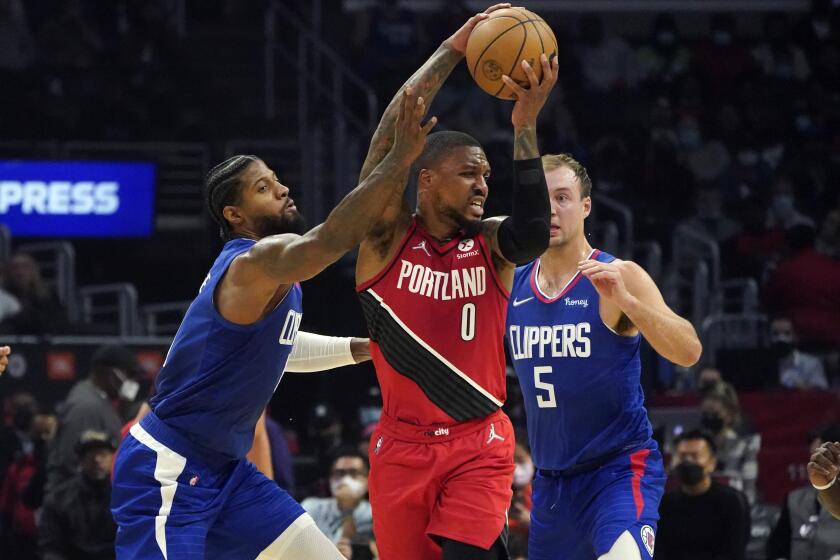 Los Angeles Clippers guard Paul George, left, and guard Luke Kennard (5) defend against Portland Trail Blazers guard Damian Lillard (0) during the first half of an NBA basketball game Monday, Oct. 25, 2021, in Los Angeles. (AP Photo/Marcio Jose Sanchez)