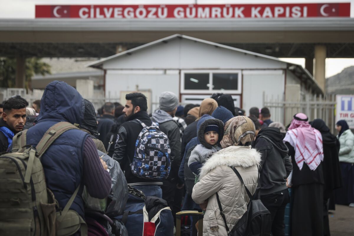 A group of people gather near a border crossing 