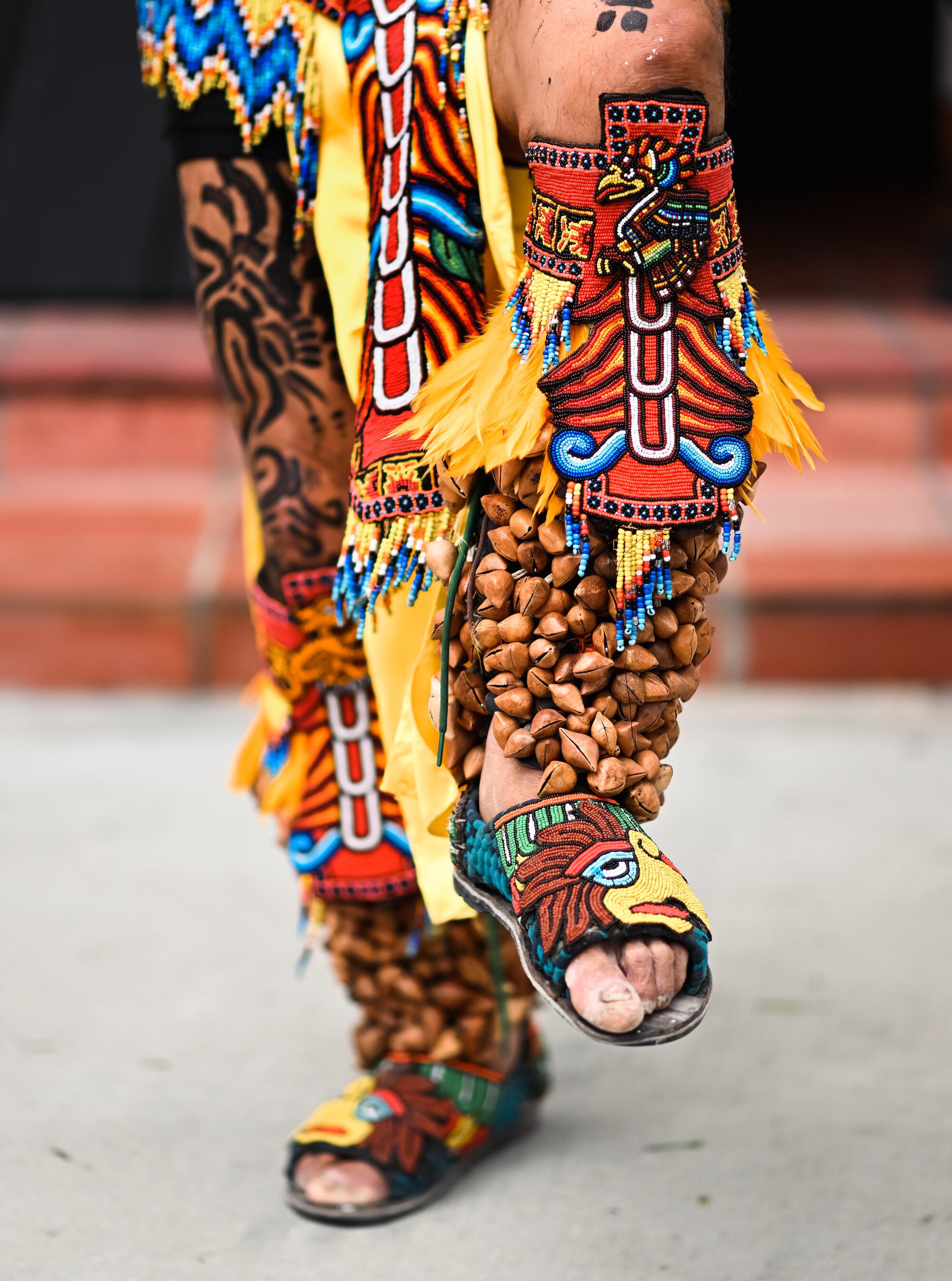 A close-up of two legs in regalia dancing
