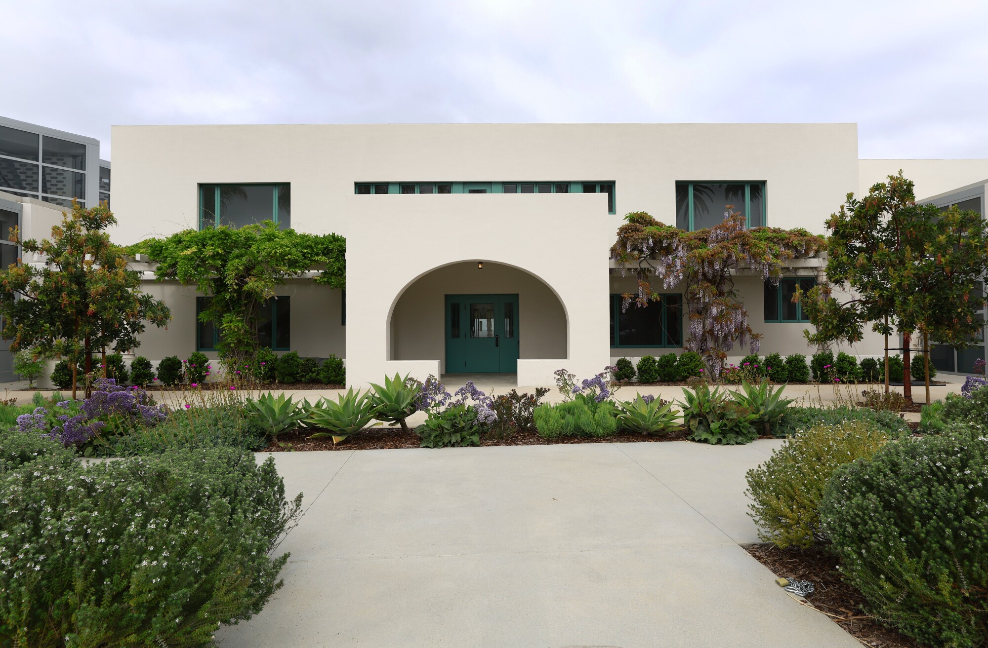 An arched Modernist sunporch designed by Irving Gill is framed by plantings.