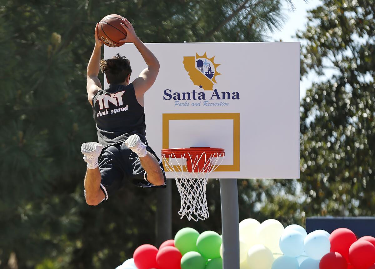 A member of the TNT Dunk Squad uses a trampoline to dunk at the basketball courts at Portola Park.