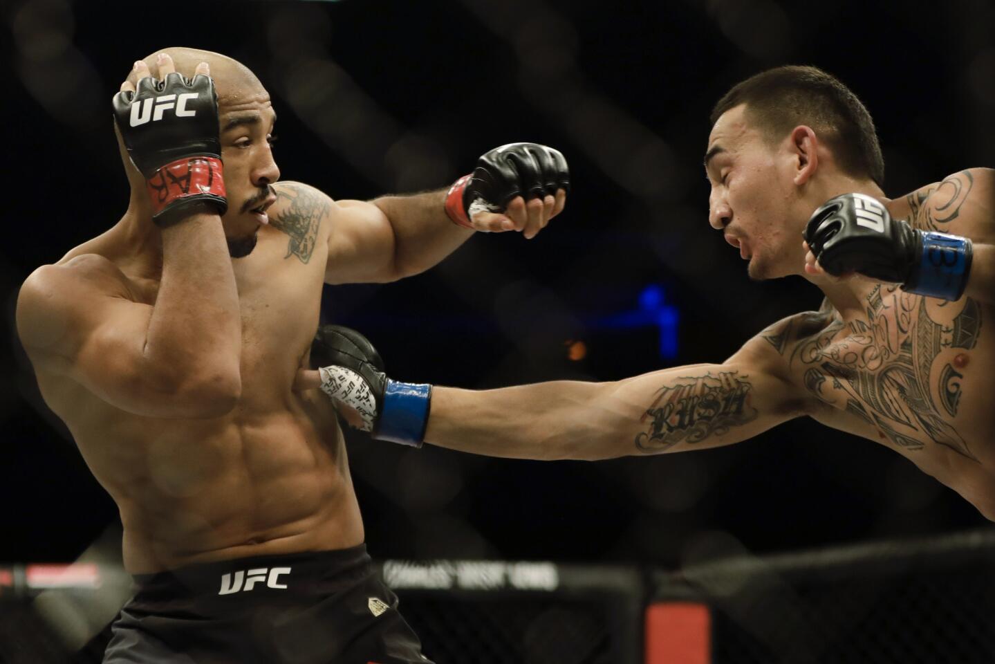 Jose Aldo, left, of Brazil, left, is hit by Max Holloway, of the United States, during their UFC featherweight mixed martial arts bout in Rio de Janeiro, Brazil, early Sunday, June 4, 2017. (AP Photo/Leo Correa)