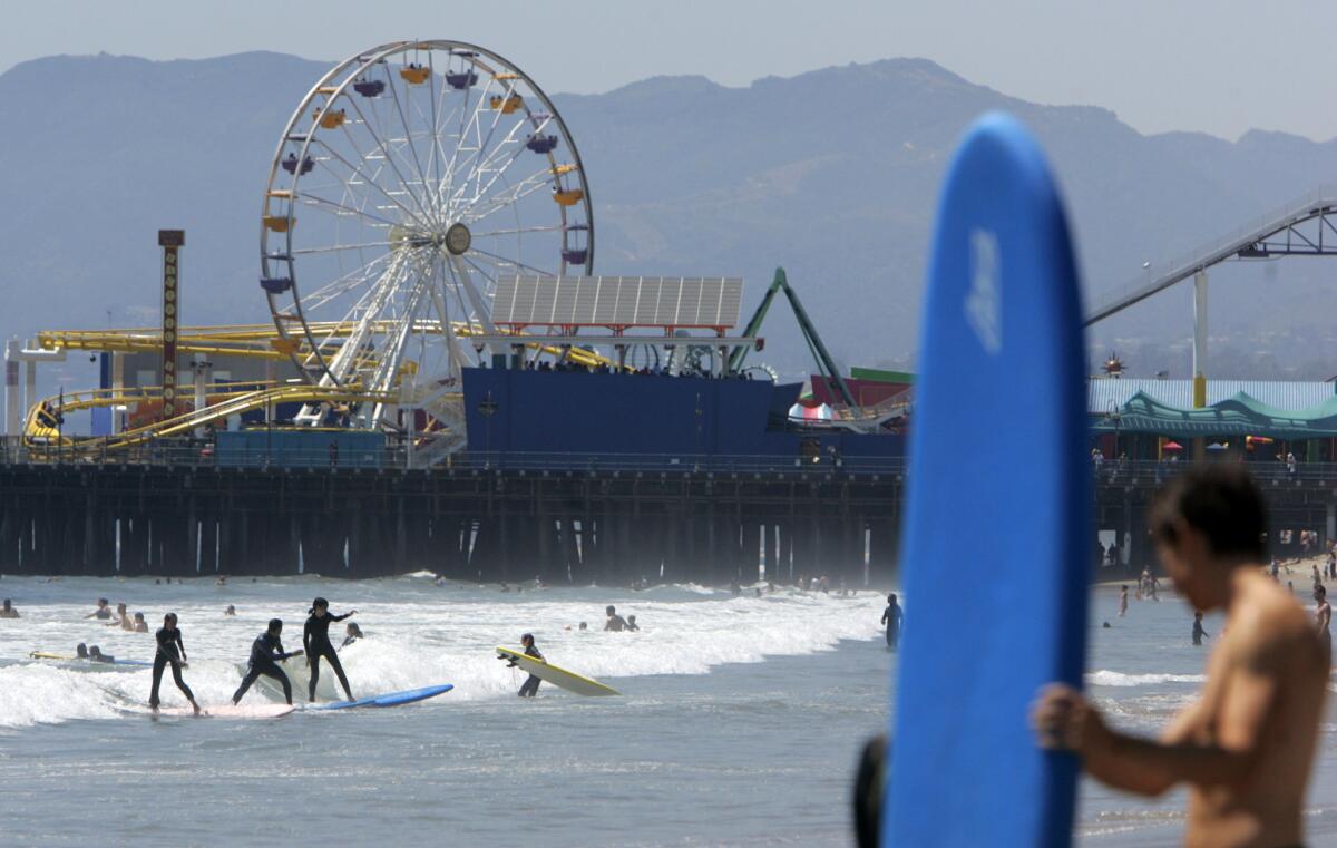 Surfers hit the ocean near the Santa Monica Pier, a few blocks from where the Expo Line will stop.