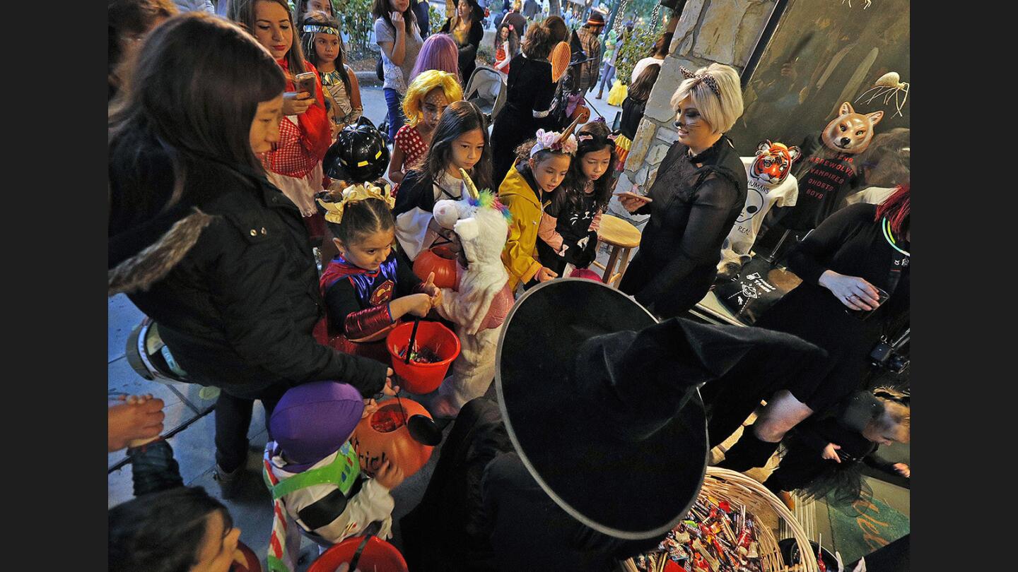 Trick-or-treaters swarm Taylor Wolfe, of Glendale, who is dressed as a witch sitting in front of Veruca Salt at the Montrose Trick-or-Treat Spooktacular on Honolulu Avenue on Tuesday, October 31, 2017.