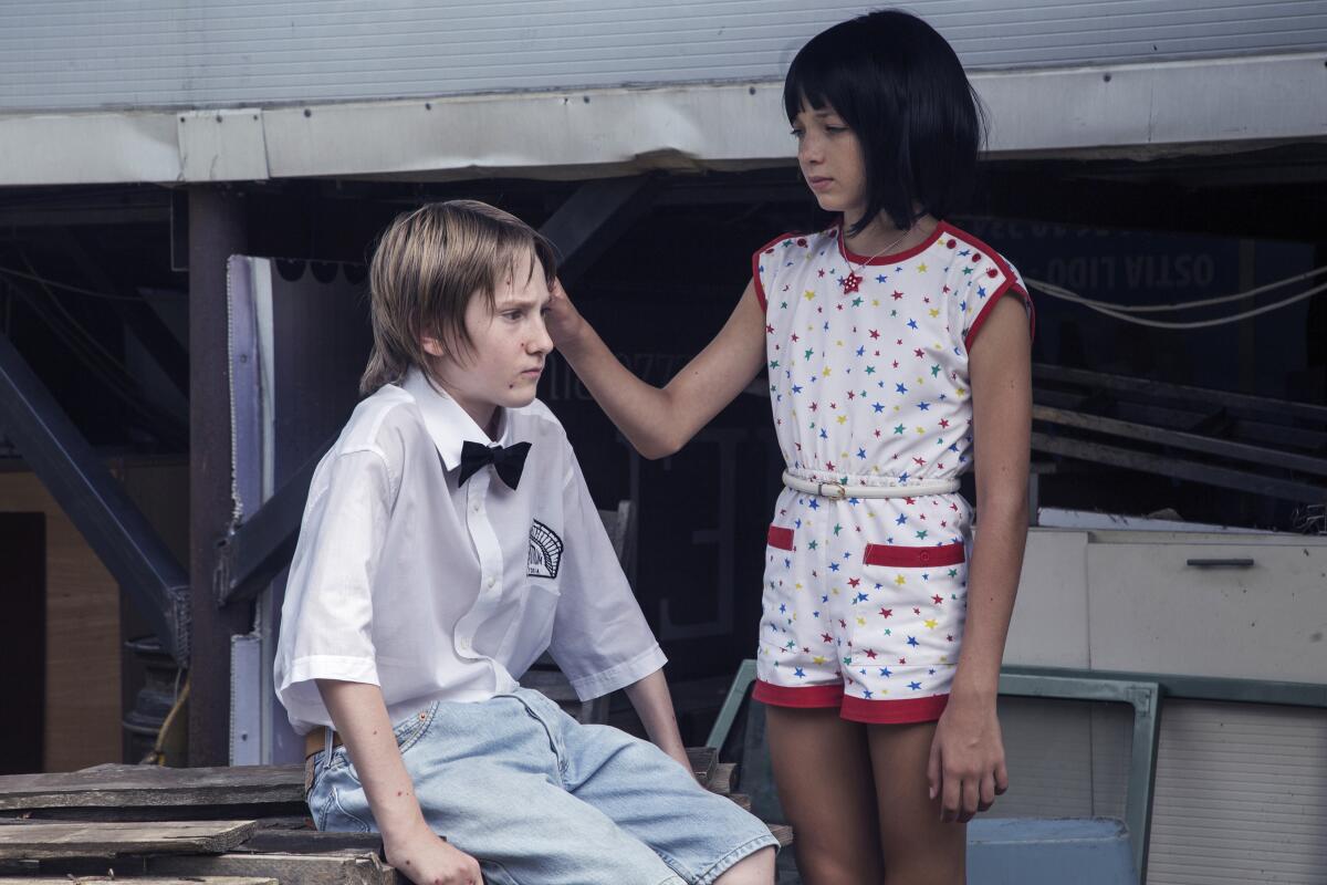 A girl touches the hair of a boy wearing a bow tie