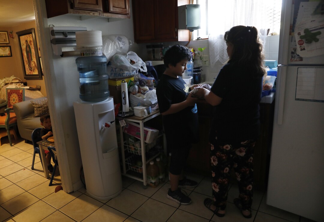Glenda Valenzuela washes an apple for her son Angel, 9, at their home in Montecito Heights on Aug. 4. 
