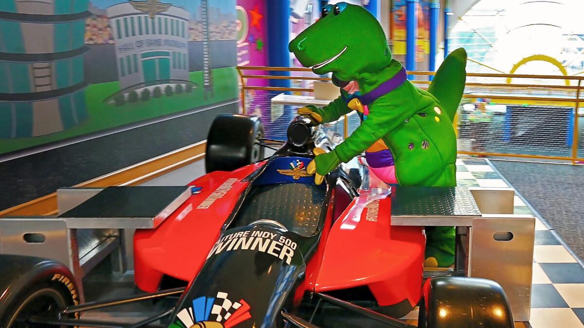 A dinosaur checks out an Indy race car, part of the learning experiences offered at the Children's Museum of Indianapolis.