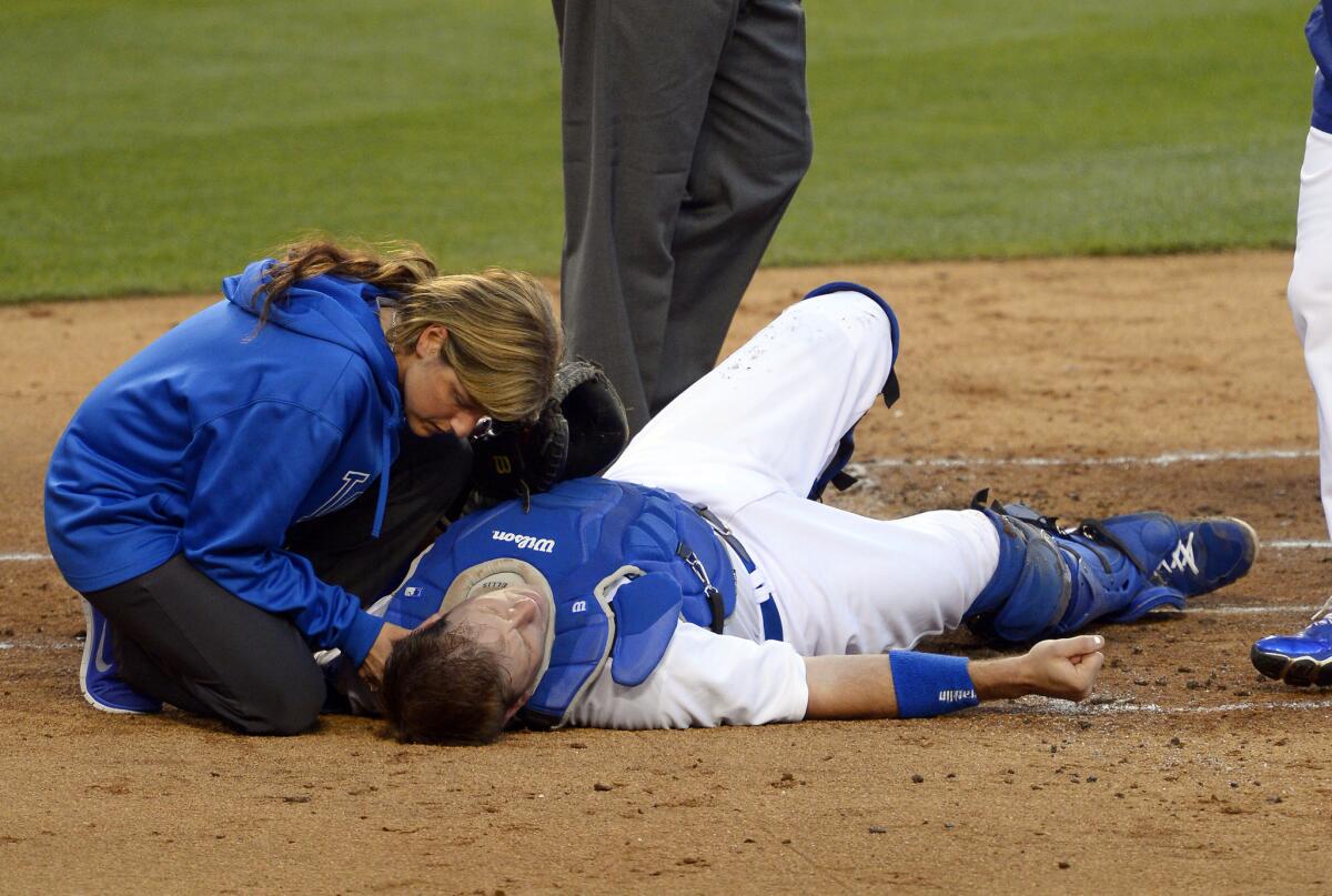 Dodgers catcher A.J. Ellis is evaluated by trainer Sue Falsone after he was knocked flat by a collision with Cardinals center fielder Jon Jay on a play at home plate in the second inning Friday night.