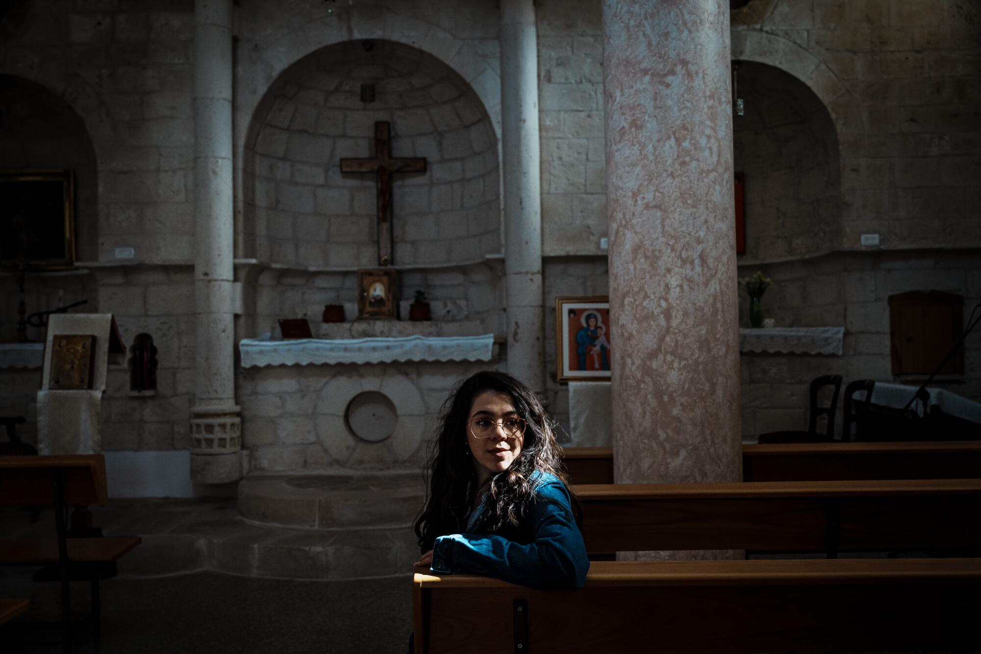 Maryam Younnes sitzt im Lichtstrahl, der in eine alte maronitische Kirche scheint 