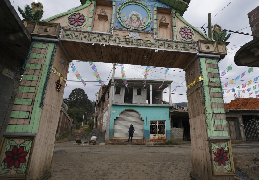 A community police officer stands guard at the main gate to the Purepecha Indigenous community of Comachuen, Michoacan state, Mexico, Wednesday, Jan. 19, 2022. In Comachuen the whole town survives because of the money sent home by migrants working in the United States. (AP Photo/Fernando Llano)