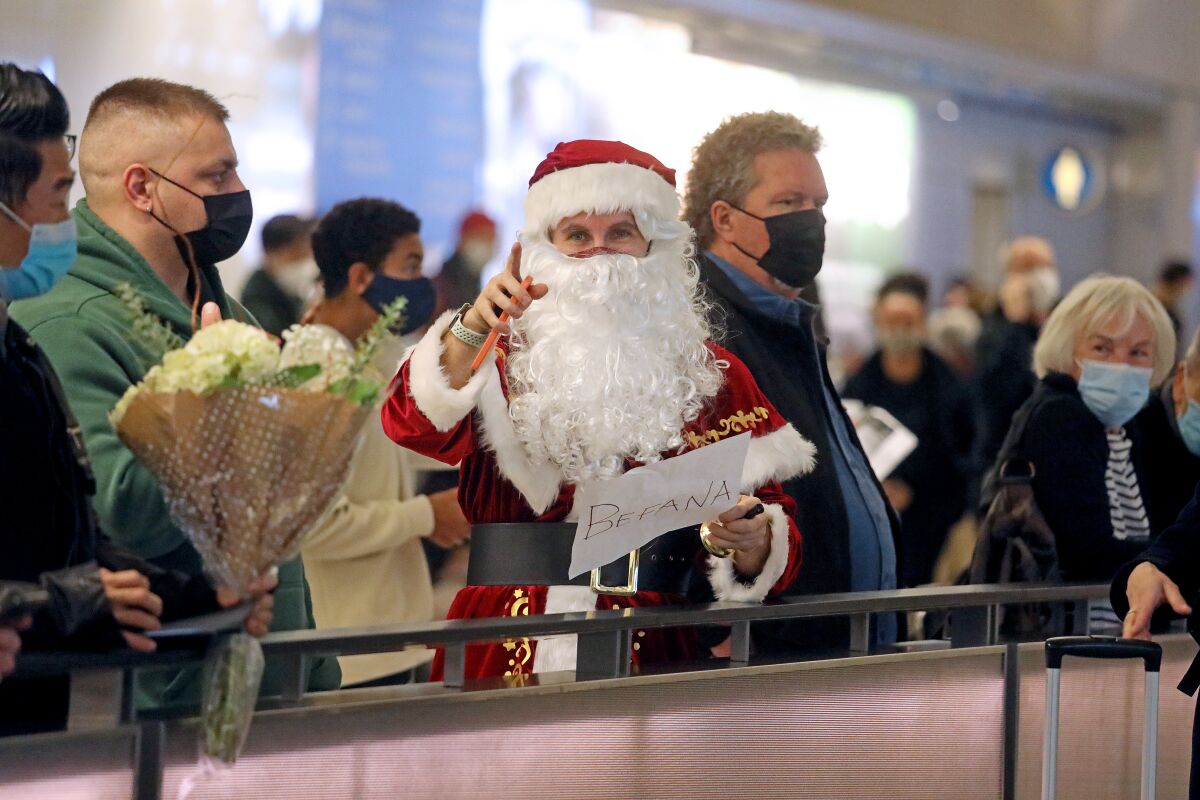 A Santa waits for someone at an airport terminal.