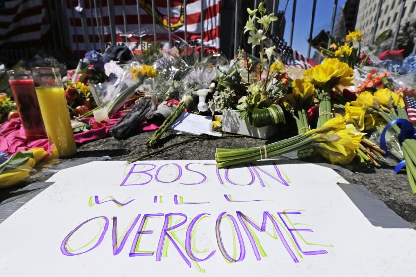 FILE - In this April 17, 2013 photograph, flowers and signs adorn a barrier, two days after two explosions killed three and injured hundreds, at Boylston Street near the of finish line of the Boston Marathon at a makeshift memorial for victims and survivors of the bombing. A federal appeals court has overturned the death sentence of Dzhokhar Tsarnaev in the 2013 Boston Marathon bombing, Friday, July 31, 2020, saying the judge who oversaw the case didn't adequately screen jurors for potential biases. (AP Photo/Charles Krupa, File)