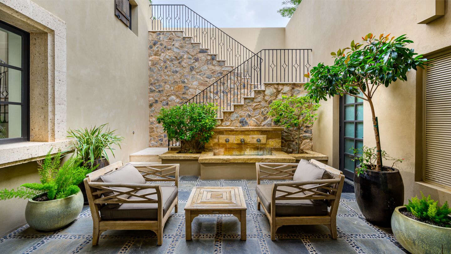 The courtyard shows furnishings, potted plants and stairs.