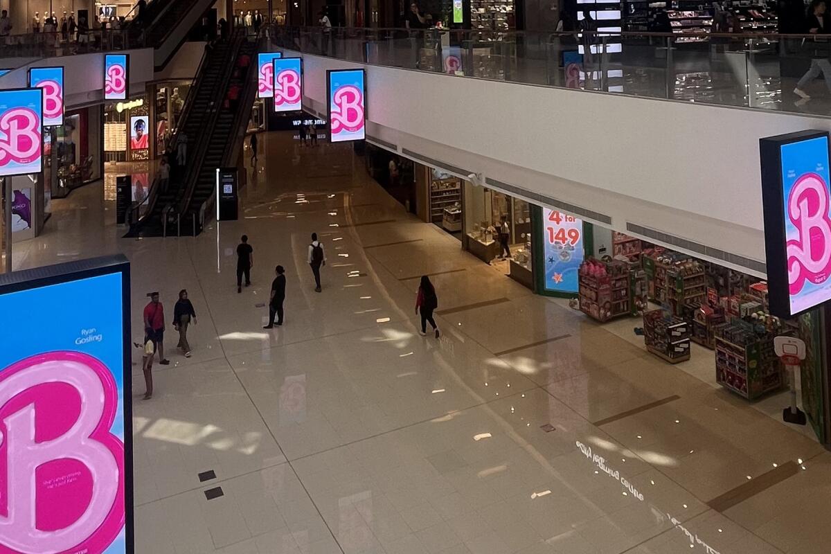 Signs with a pink "B" against a blue backdrop line the upper floor of a shopping mall 