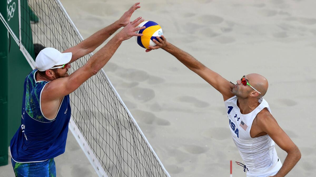 American Phil Dalhausser tries to tip the volleyball away from the block attempt of Brazil's Bruno Schmidt during a quarterfinal match in men's beach volleyball Monday.