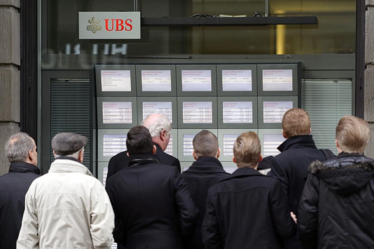 A Zurich crowd follows the currency market after Switzerland's central bank said Thursday it has scrapped a policy that limited how much the euro could fall against the Swiss franc, an unexpected decision that caused gyrations in financial markets.