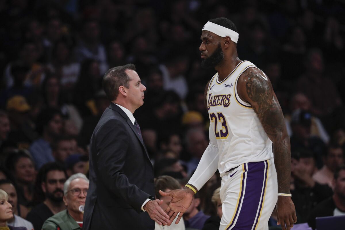 Lakers coach Frank Vogel and LeBron James slap hands along the sideline.