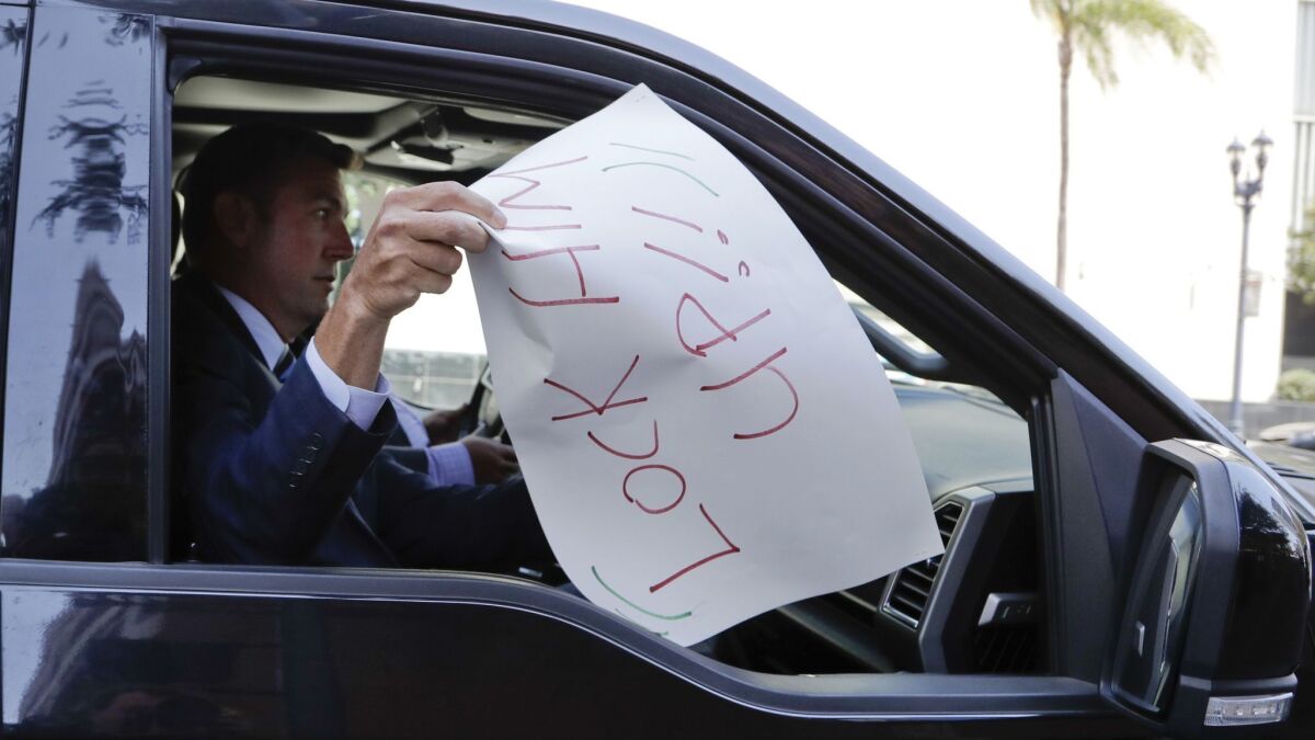 U.S. Rep. Duncan Hunter removes a sign that reads "lock him up" that was placed on the windshield of his car by a protester last year.