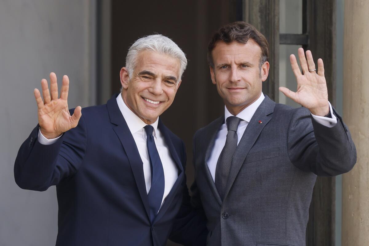 French President Emmanuel Macron, right, and Israel's Prime Minister Yair Lapid wave Tuesday, July 5, 2022 at the Elysee Palace in Paris. It was the first overseas trip by Yair Lapid since he took office last week. (AP Photo/Thomas Padilla)