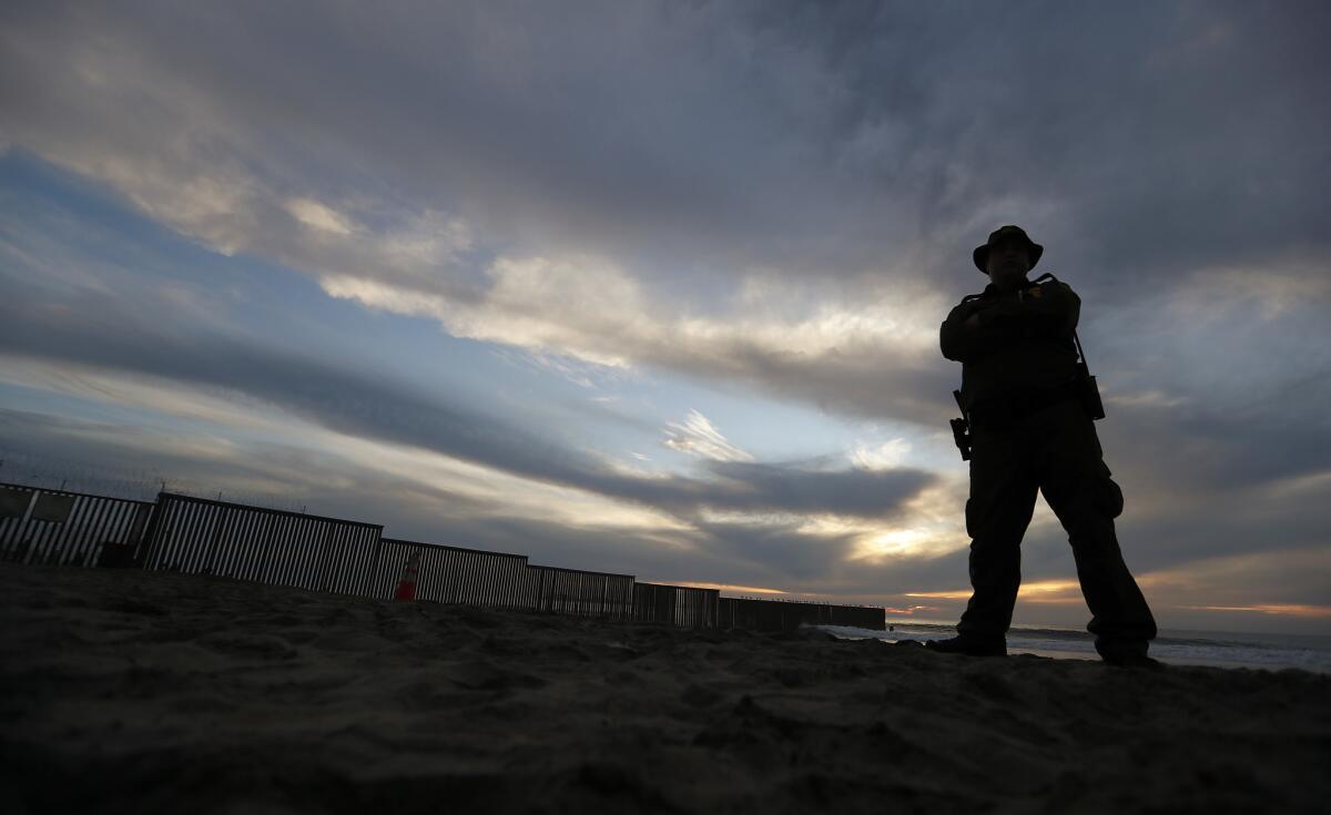 A Border Patrol officer stands watch near the border wall where it runs into the Pacific Ocean at Imperial Beach.