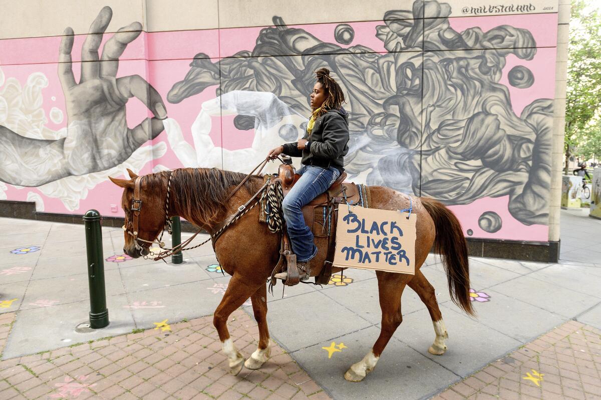 Brianna Noble rides her horse, Dapper Dan, through downtown Oakland on May 29.