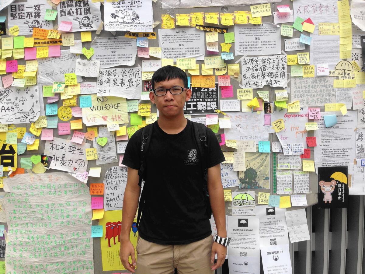 Kelvin Chan, 23, stands in front of a wall of pro-democracy messages in Hong Kong's Admiralty district. He says his father doesn't support his activism.