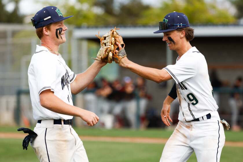 San Diego, CA - April 04: Del Norte's Griffen Gusich (2) and Landon Cheshire (9) high five at the dugout during their game against Torrey Pines at Del Norte High School on Thursday, April 4, 2024 in San Diego, CA. (Meg McLaughlin / The San Diego Union-Tribune)