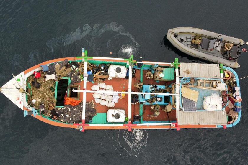 In this aerial photo released by the U.S. Navy, U.S. service members from coastal patrol ship USS Tempest (PC 2) and USS Typhoon (PC 5) inventory an illicit shipment of drugs while aboard a stateless dhow vessel transiting international waters in the Arabian Sea, Dec. 27, 2021. United States navy vessels seized 385 kilograms (849 pounds) of heroin in the Arabian Sea worth some $4 million in a major bust by the international maritime operation in the region, officials said Thursday. (U.S. Navy photo Via AP)