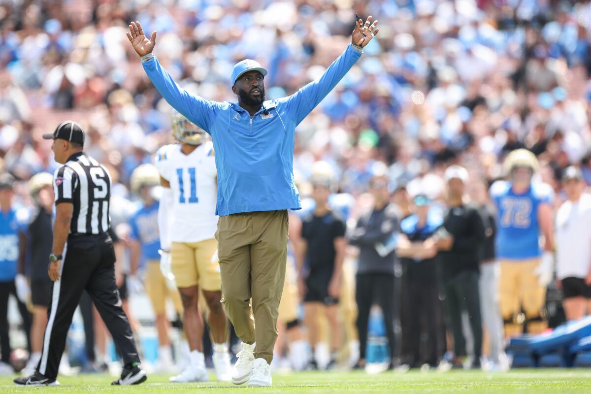 UCLA coach DeShaun Foster raises his arms during the Bruins' spring football showcase at the Rose Bowl