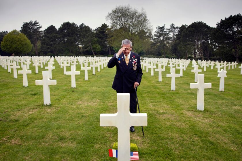 In this May 1, 2019 file photo, World War II and D-Day veteran Charles Norman Shay, from Indian Island, Maine, salutes the grave of fellow soldier Edward Morozewicz at the Normandy American Cemetery in Colleville-sur-Mer, Normandy, France. Instead of parades, remembrances, embraces and one last great hurrah for veteran soldiers who are mostly in their nineties to celebrate VE Day, it is instead a lockdown due to the coronavirus, COVID-19. (AP Photo/Virginia Mayo, File)