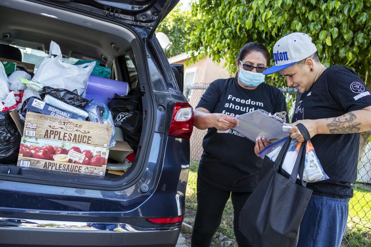 Stacy Rojas, right, and Dolores Canales of the Compton Bail Project check paperwork as they load supplies.