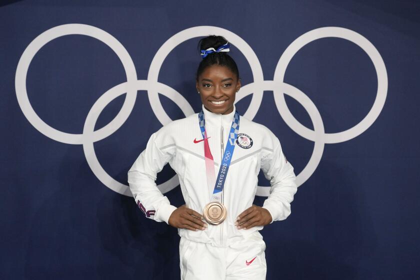 FILE - Simone Biles, of the United States, poses wearing her bronze medal from balance beam competition during artistic gymnastics at the 2020 Summer Olympics, Aug. 3, 2021, in Tokyo, Japan. President Joe Biden will present the nation’s highest civilian honor, the Presidential Medal of Freedom, to 17 people, at the White House next week. (AP Photo/Natacha Pisarenko, File)