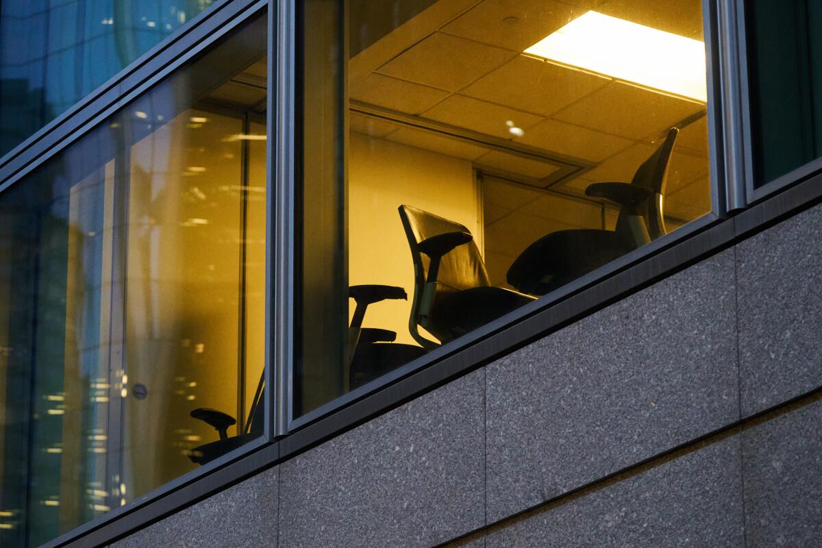 Empty office chairs seen through an upper-floor window.