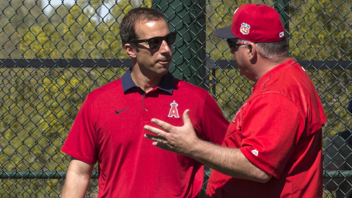Angels General Manager Billy Eppler chats with Manager Mike Scioscia behind the batting cage during a spring-training workout at Tempe Diablo Stadium on Feb. 26.