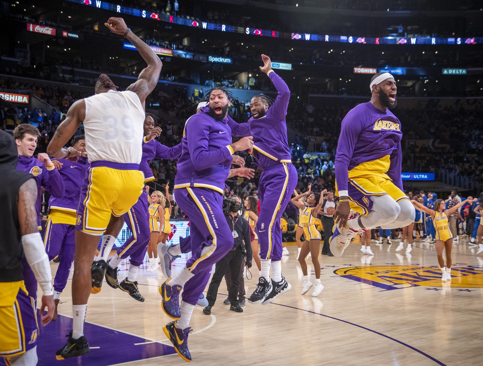 Basketball players in purple-and-yellow uniforms jump on the court 