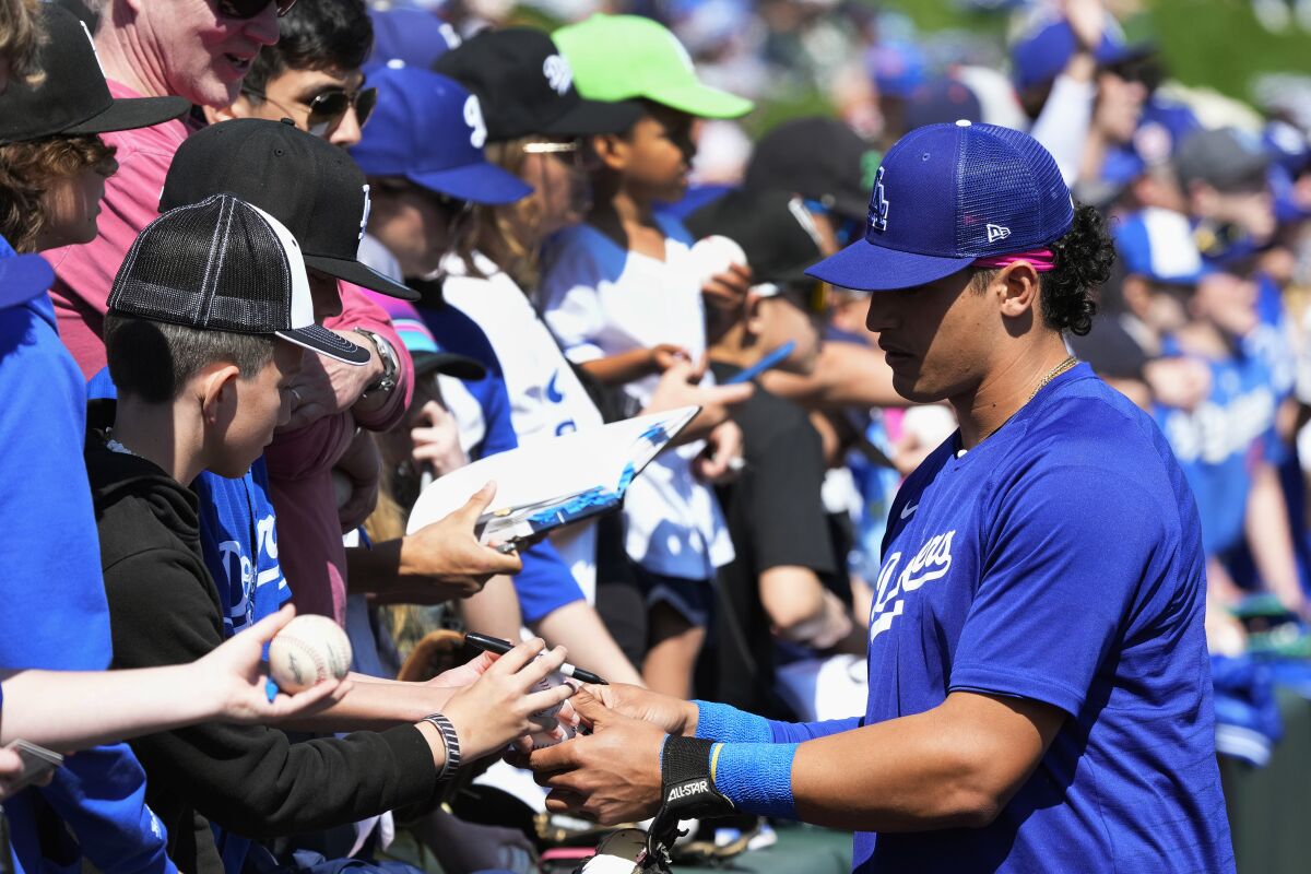 Dodgers catcher Diego Cartaya, right, signs autographs before a spring-training game against the Angels on March 3.