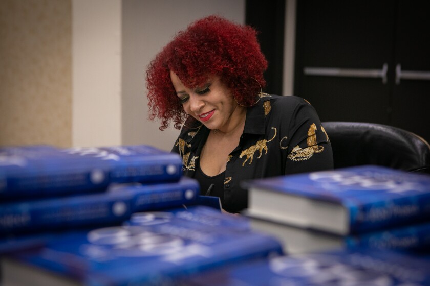A woman sitting behind a stack of books.