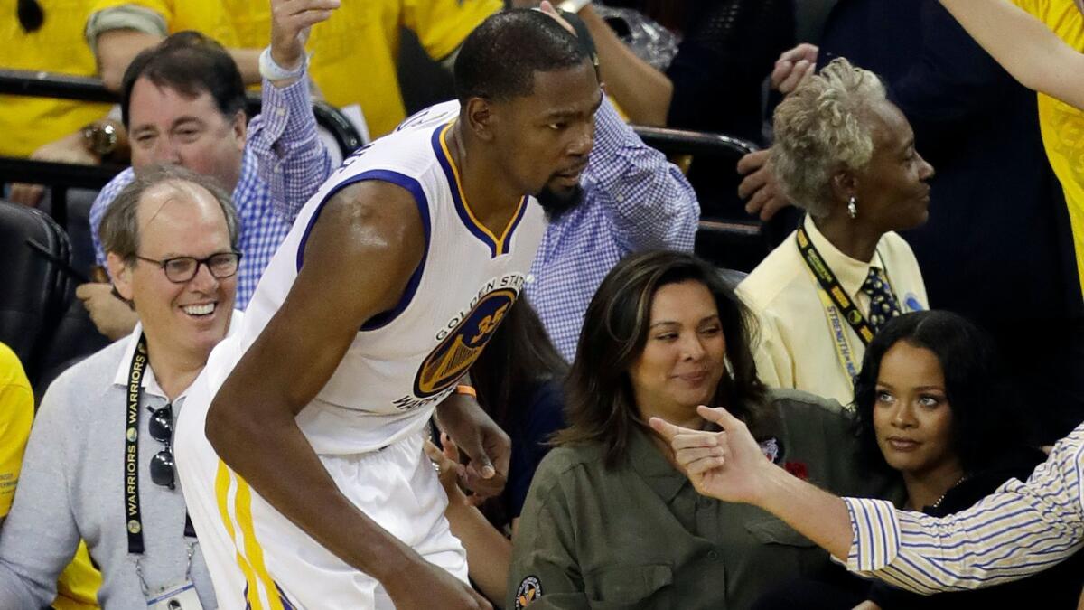 Pop star Rihanna, bottom right, watches as Golden State's Kevin Durant runs past during Game 1 of the NBA Finals in Oakland on June 1.