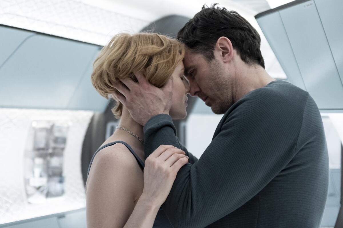 A woman and a man embrace on a spaceship.