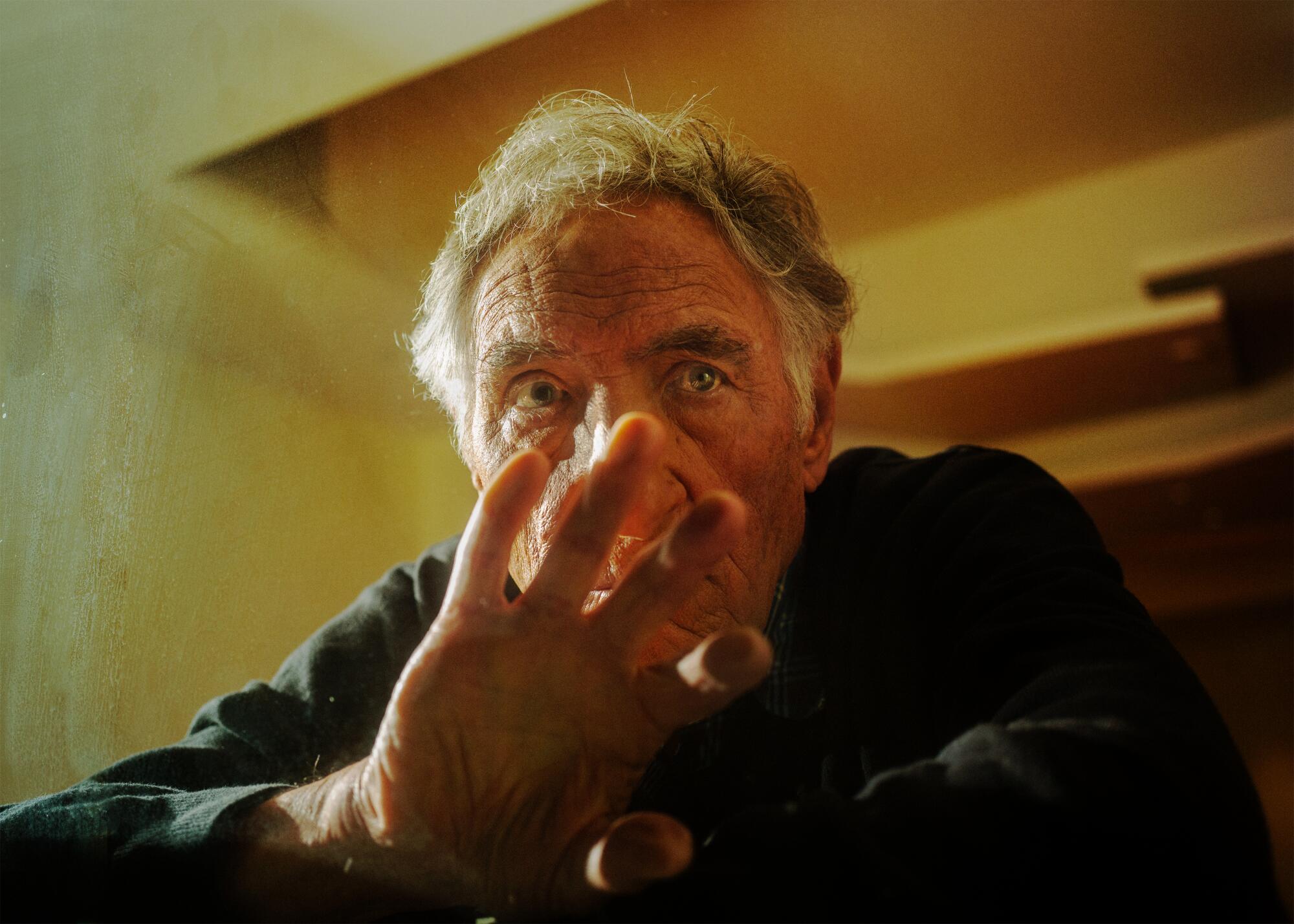 Judd Hirsch holds up his hand in front of the lower half of his face. 