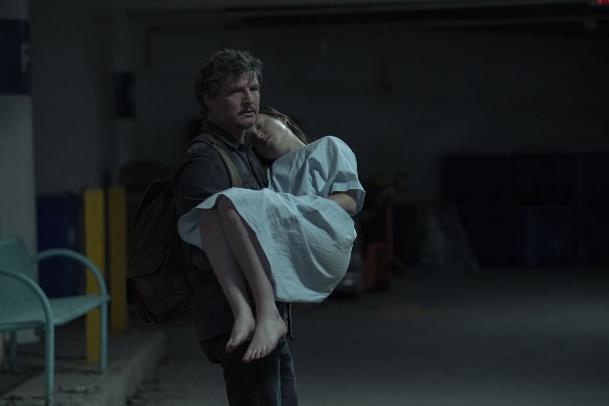 A man carrying a teenage girl wearing a hospital gown.