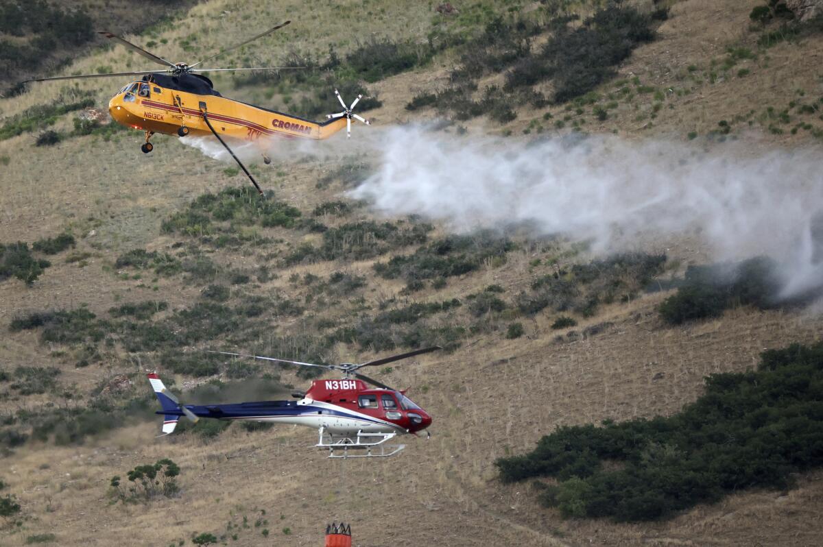 Dos helicópteros combaten un incendio en Springville, Utah, el lunes 1 de agosto de 2022. 