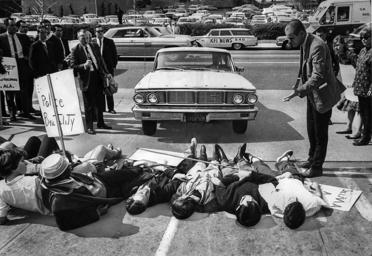 March 10, 1965: Deputy U.S. marshal, right, speaks to group of demonstrators who are lying across a parking lot entrance to L.A.'s Federal Building.