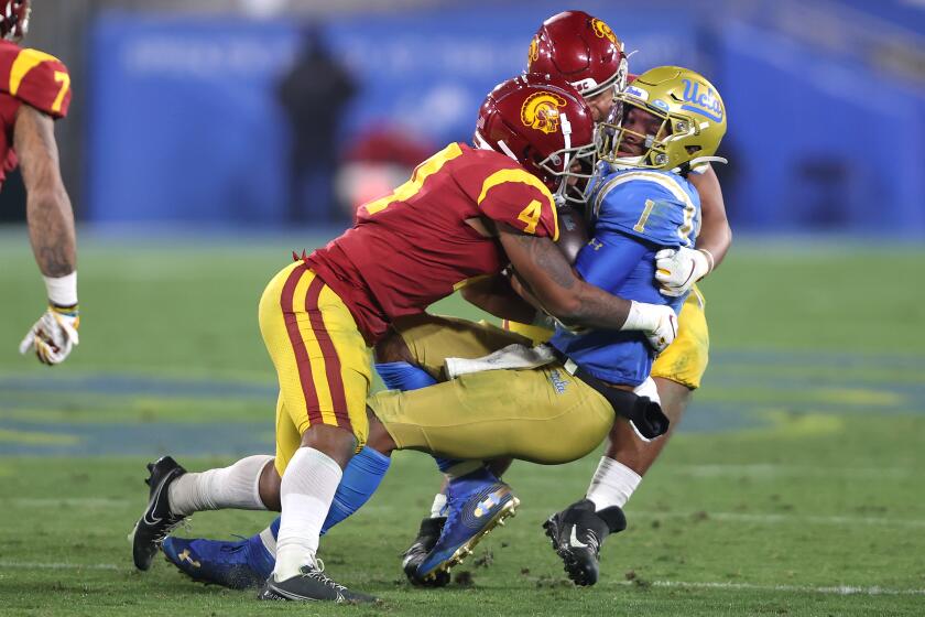 PASADENA, CALIFORNIA - DECEMBER 12: Max Williams #4 and Tuli Tuipulotu #49 of the USC Trojans tackle Dorian Thompson-Robinson #1 of the UCLA Bruins during the second half of a game at the Rose Bowl on December 12, 2020 in Pasadena, California. (Photo by Sean M. Haffey/Getty Images)